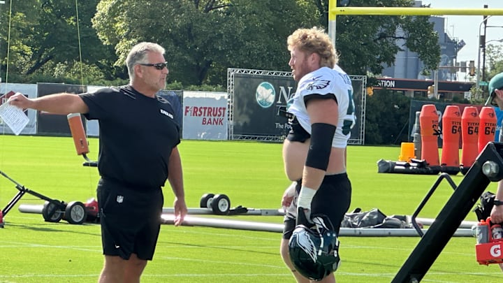 Offensive line coach Jeff Stoutland (left) gives center Cam Jurgens direction during a drill at Eagles training camp.