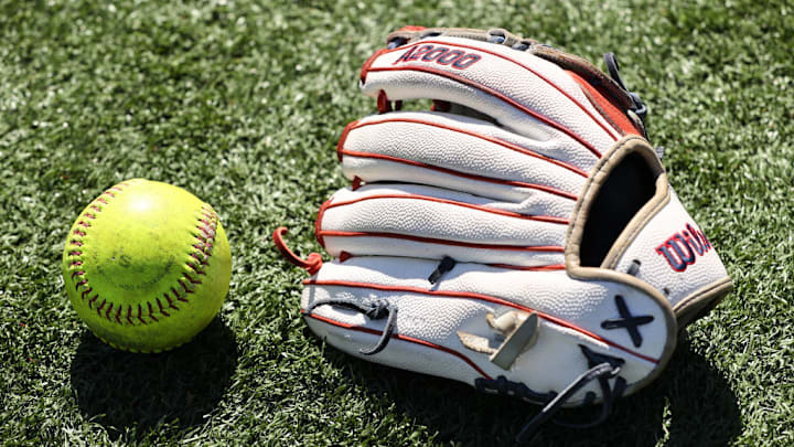 A softball and a softball glove on the field. A softball and a softball glove on the field.