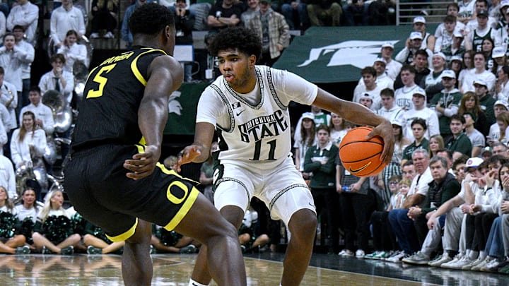 Feb 8, 2025; East Lansing, Michigan, USA; Michigan State Spartans guard Jase Richardson (11) looks for a way around Oregon Ducks guard TJ Bamba (5) during the second half at Jack Breslin Student Events Center. Mandatory Credit: Dale Young-Imagn Images