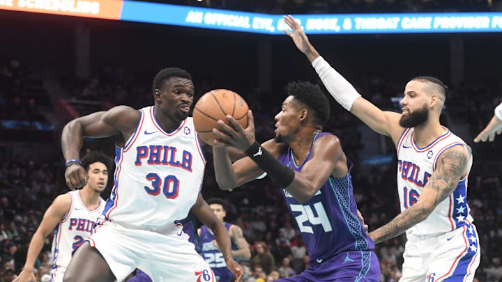 Dec 3, 2024; Charlotte, North Carolina, USA;  Charlotte Hornets forward Brandon Miller (24) looks to shoot through the defense of Philadelphia 76ers center Adam Bona (30) and forward Caleb Martin (11) during the second half at the Spectrum Center. Mandatory Credit: Sam Sharpe-Imagn Images