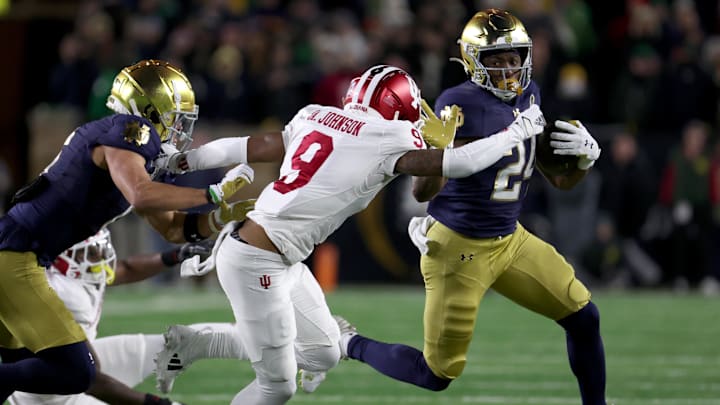 Dec 20, 2024; Notre Dame, Indiana, USA; Notre Dame Fighting Irish running back Jadarian Price (24) runs against Indiana Hoosiers defensive back Jamier Johnson (9) during the first half at Notre Dame Stadium. Mandatory Credit: Trevor Ruszkowski-Imagn Images