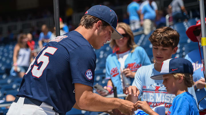 Jun 26, 2022; Omaha, NE, USA; Ole Miss Rebels pitcher Mason Nichols (45) signs a baseball for a fan before the game against the Oklahoma Sooners at Charles Schwab Field. Mandatory Credit: Steven Branscombe-Imagn Images
