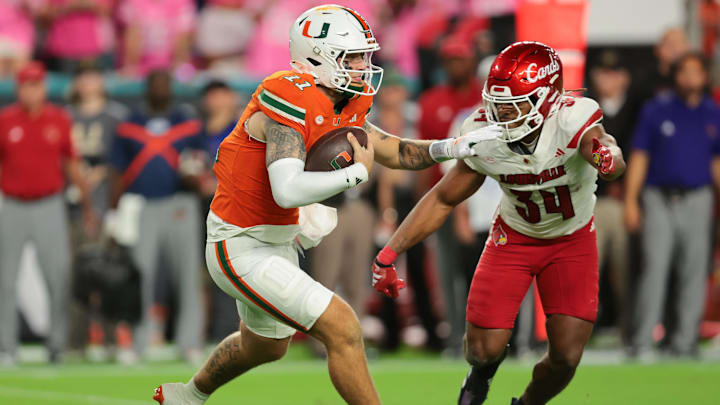 Oct 17, 2025; Miami Gardens, Florida, USA; Miami Hurricanes quarterback Carson Beck (11) carries the football against Louisville Cardinals linebacker T.J. Quinn (34) during the third quarter at Hard Rock Stadium. Mandatory Credit: Sam Navarro-Imagn Images