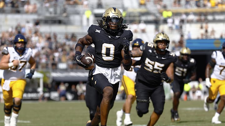Oct 18, 2025; Orlando, Florida, USA;  Central Florida Knights linebacker Keli Lawson (0) scoops a fumble and returns it for a second half touchdown against the West Virginia Mountaineers at Acrisure Bounce House. Mandatory Credit: Russell Lansford-Imagn Images