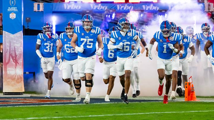 Jan 8, 2026; Glendale, AZ, USA; Mississippi Rebels players run onto the field prior to the game against the Miami Hurricanes during the 2026 Fiesta Bowl and semifinal game of the College Football Playoff at State Farm Stadium. Mandatory Credit: Mark J. Rebilas-Imagn Images