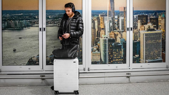 Man in a jacket waits by his suitcase in an airport