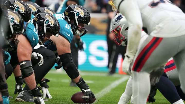 Oct 20, 2024; London, United Kingdom; Helmets at the line fo scrimmage as Jacksonville Jaguars center Mitch Morse (65) snaps the ball against the New England Patriots in the second half of an NFL International Series game at Wembley Stadium. Mandatory Credit: Kirby Lee-Imagn Images