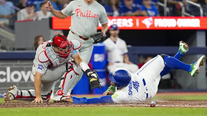 Jun 10, 2026; Toronto, Ontario, CAN;  Toronto Blue Jays designated hitter George Springer #4 slides into home plate against Philadelphia Phillies catcher J.T. Realmuto #10 during the seventh inning at Rogers Centre. Mandatory Credit: Kevin Sousa-Imagn Images