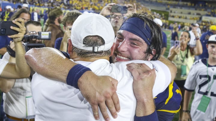 Sep 13, 2025; Morgantown, West Virginia, USA; West Virginia Mountaineers head coach Rich Rodriguez celebrates with West Virginia Mountaineers quarterback Nicco Marchiol (8) after defeating the Pittsburgh Panthers at Milan Puskar Stadium. Mandatory Credit: Ben Queen-Imagn Images Sep 13, 2025; Morgantown, West Virginia, USA; West Virginia Mountaineers head coach Rich Rodriguez celebrates with West Virginia Mountaineers quarterback Nicco Marchiol (8) after defeating the Pittsburgh Panthers at Milan Puskar Stadium. Mandatory Credit: Ben Queen-Imagn Images