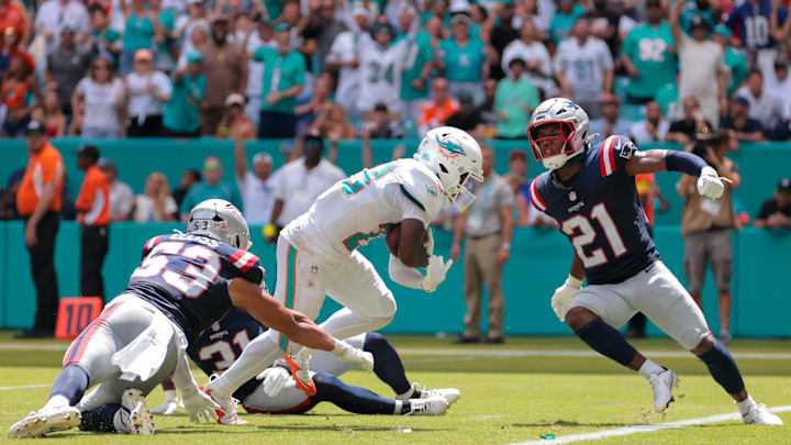 Miami Dolphins running back De'Von Achane (28) carries the football for a touchdown against New England Patriots safety Jaylinn Hawkins (21), linebacker Christian Elliss (53) and safety Craig Woodson (31) during the second quarter at Hard Rock Stadium. 