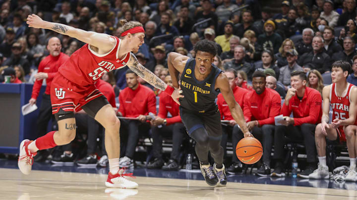 Feb 8, 2025; Morgantown, West Virginia, USA; West Virginia Mountaineers guard Joseph Yesufu (1) drives past Utah Utes guard Gabe Madsen (55) during the first half at WVU Coliseum. Mandatory Credit: Ben Queen-Imagn Images