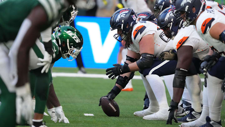 Oct 12, 2025; Tottenham, United Kingdom; Helmets at the line of scrimmage as Denver Broncos center Luke Wattenberg (60) snaps the ball against the New York Jets during an NFL International Series game at Tottenham Hotspur Stadium. Mandatory Credit: Kirby Lee-Imagn Images