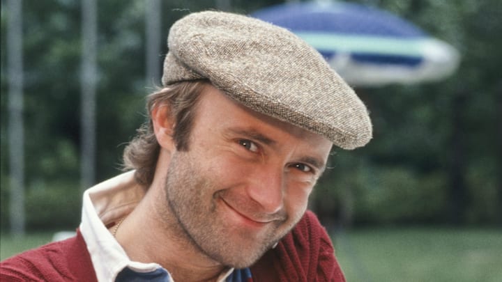 Phil Collins posing with the Telegatto award he won