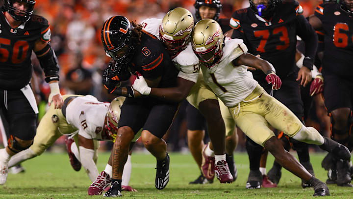 Oct 26, 2024; Miami Gardens, Florida, USA; Miami Hurricanes running back Damien Martinez (6) runs with the football against Florida State Seminoles defensive lineman KJ Sampson (56) and defensive back Shyheim Brown (1) during the fourth quarter at Hard Rock Stadium. Mandatory Credit: Sam Navarro-Imagn Images