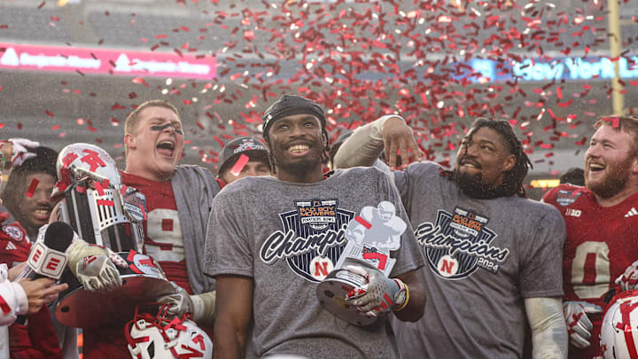 Nebraska Cornhuskers running back Rahmir Johnson (14) holds the most valuable player trophy and celebrates with teammates