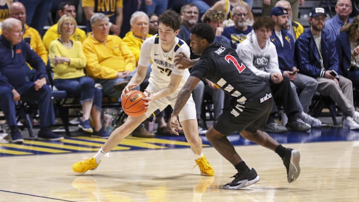 Jan 6, 2026; Morgantown, West Virginia, USA; West Virginia Mountaineers guard Treysen Eaglestaff (52) and Cincinnati Bearcats guard Jizzle James (2) fight for a loose ball during the second half at Hope Coliseum. Mandatory Credit: Ben Queen-Imagn Images