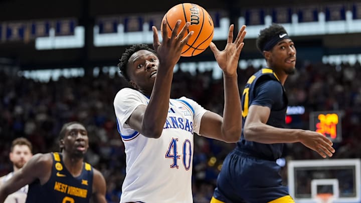 Dec 31, 2024; Lawrence, Kansas, USA; Kansas Jayhawks forward Flory Bidunga (40) grabs a loose ball against West Virginia Mountaineers guard Sencire Harris (10) and center Eduardo Andre (0) during the second half at Allen Fieldhouse. Mandatory Credit: Jay Biggerstaff-Imagn Images