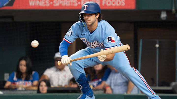 Texas Rangers shortstop Josh Smith lays down a bunt single with his bat.