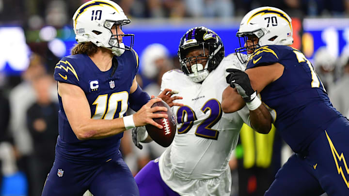 Nov 26, 2023; Inglewood, California, USA; Los Angeles Chargers quarterback Justin Herbert (10) moves out to pass as offensive tackle Rashawn Slater (70) provides coverage against Baltimore Ravens defensive tackle Justin Madubuike (92) during the first half at SoFi Stadium. Mandatory Credit: Gary A. Vasquez-Imagn Images