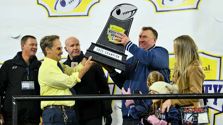 Dec 30, 2025; Nashville, TN, USA;  Illinois Fighting Illini head coach Bret Bielema hoist the trophy with Doug from Liberty Mutual against the Tennessee Volunteers during the second half at Nissan Stadium. Mandatory Credit: Steve Roberts-Imagn Images