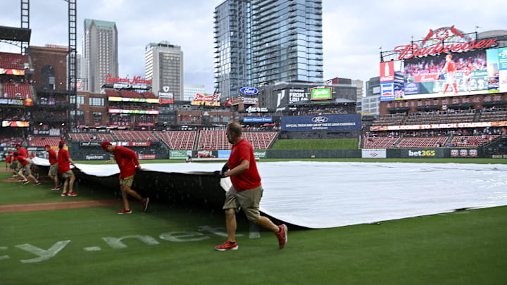 Jul 13, 2025; St. Louis, Missouri, USA;  St. Louis Cardinals grounds crew pulls the tarp on the field during a rain delay in the third inning of a game between the St. Louis Cardinals and the Atlanta Braves at Busch Stadium. Mandatory Credit: Jeff Curry-Imagn Images