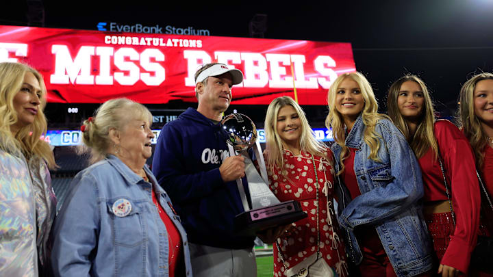 Mississippi Rebels head coach Lane Kiffin, center left, poses with the Ash Verlander Champions Trophy with his family after the game of the TaxSlayer Gator Bowl.
