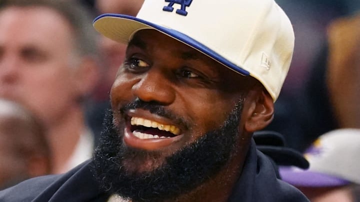 Oct 5, 2025; San Francisco, California, USA;  Los Angeles Lakers forward LeBron James (23), wearing a Los Angeles Dodgers hat, smiles after watching his son, guard Bronny James (9), dunk a rebound against the Golden State Warriors in the third quarter at Chase Center. Mandatory Credit: David Gonzales-Imagn Images