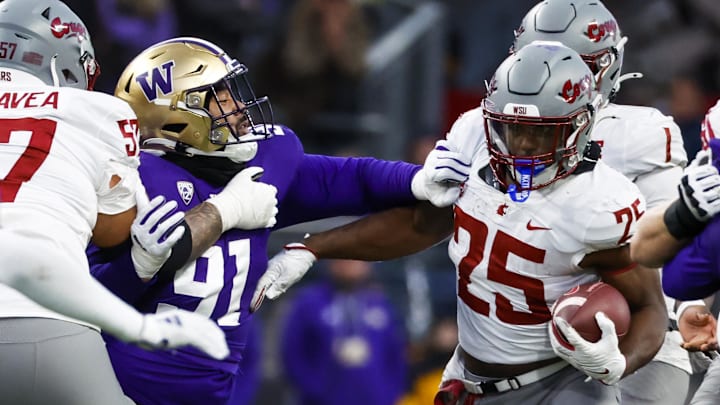 Nov 25, 2023; Seattle, Washington, USA; Washington Huskies defensive lineman Tuli Letuligasenoa (91) tackles Washington State Cougars running back Nakia Watson (25) during the fourth quarter at Alaska Airlines Field at Husky Stadium. Mandatory Credit: Joe Nicholson-Imagn Images