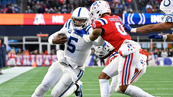 Dec 1, 2024; Foxborough, Massachusetts, USA; New England Patriots cornerback Christian Gonzalez (0) tackles Indianapolis Colts quarterback Anthony Richardson (5) during the second half at Gillette Stadium. Mandatory Credit: Eric Canha-Imagn Images