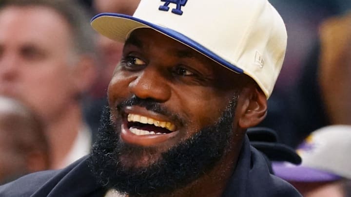 Oct. 5, 2025; San Francisco, California, USA;  Los Angeles Lakers forward LeBron James (23), wearing a Los Angeles Dodgers hat, smiles after watching his son, guard Bronny James (9), dunk a rebound against the Golden State Warriors in the third quarter at Chase Center.