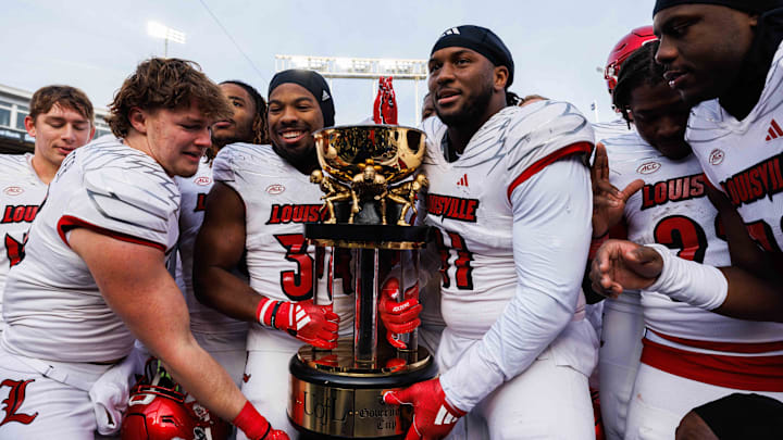 Nov 30, 2024; Lexington, Kentucky, USA; Louisville Cardinals defensive lineman Ramon Puryear (41) and Louisville Cardinals defensive back Jathan Hatch (31) hold up the Governor’s Cup trophy after winning against the Kentucky Wildcats at Kroger Field. Mandatory Credit: Jordan Prather-Imagn Images