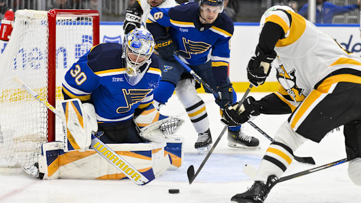 Apr 3, 2025; St. Louis, Missouri, USA;  St. Louis Blues goaltender Joel Hofer (30) defends the net against Pittsburgh Penguins right wing Bryan Rust (17) during the first period at Enterprise Center. Mandatory Credit: Jeff Curry-Imagn Images