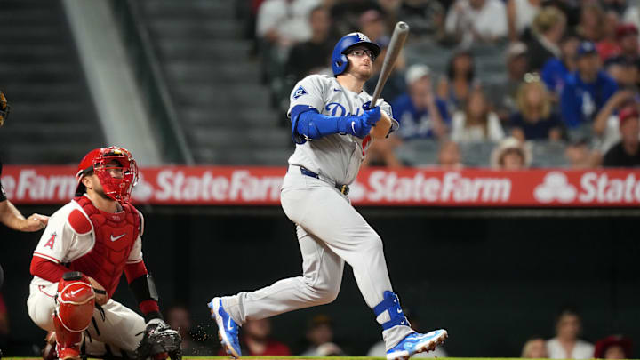 Aug 11, 2025; Anaheim, California, USA; Los Angeles Dodgers third baseman Max Muncy (13) hits a three-run home run in the eighth inning as Los Angeles Angels catcher Travis d'Arnaud (25) watches at Angel Stadium. Mandatory Credit: Kirby Lee-Imagn Images