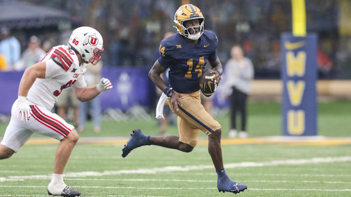 West Virginia Mountaineers quarterback Khalil Wilkins runs away from Utah Utes defensive end John Henry Daley