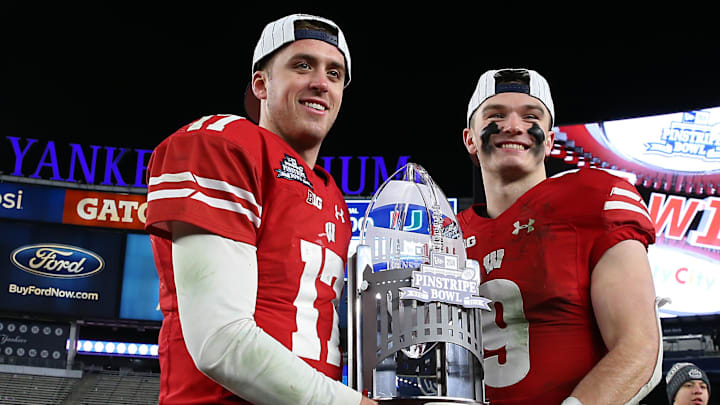 Dec 27, 2018; Bronx, NY, USA; Wisconsin Badgers quarterback Jack Coan (17) and safety Scott Nelson (9) hold the trophy after the 2018 Pinstripe Bowl against the Miami Hurricanes at Yankee Stadium. Mandatory Credit: Vincent Carchietta-Imagn Images