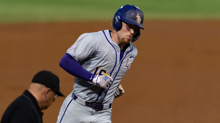 LSU Tigers player Ethan Frey jogs around the bases in a gray uniform and purple helmet. LSU Tigers player Ethan Frey jogs around the bases in a gray uniform and purple helmet.
