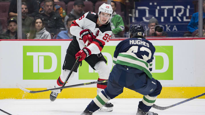 Nov 1, 2022; Vancouver, British Columbia, CAN; New Jersey Devils forward Jack Hughes (86) passes around Vancouver Canucks defenseman Quinn Hughes (43) in the second period at Rogers Arena. Mandatory Credit: Bob Frid-Imagn Images