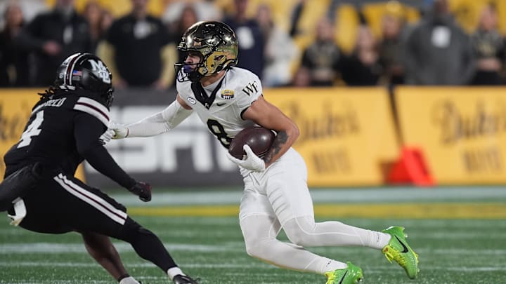 Jan 2, 2026; Charlotte, NC, USA; Wake Forest Demon Deacons wide receiver Carlos Hernandez (8) looks to elude Mississippi State Bulldogs cornerback Deago Brumfield (4) during the second quarter at Bank of America Stadium. Mandatory Credit: Jim Dedmon-Imagn Images