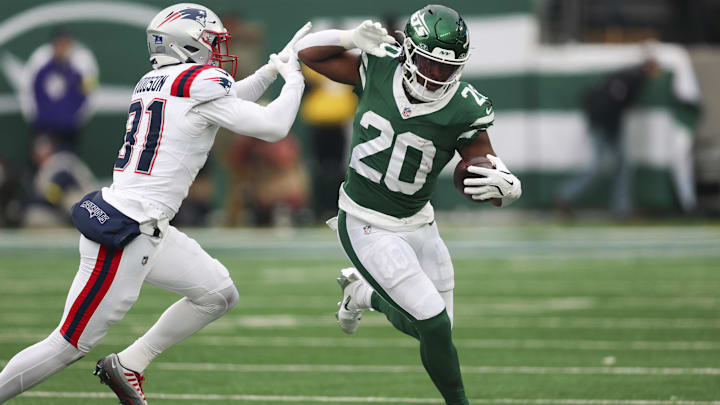 Dec 28, 2025; East Rutherford, New Jersey, USA; New York Jets running back Breece Hall (20) runs the ball against New England Patriots safety Craig Woodson (31) during the second half of the game at MetLife Stadium. Mandatory Credit: Vincent Carchietta-Imagn Images
