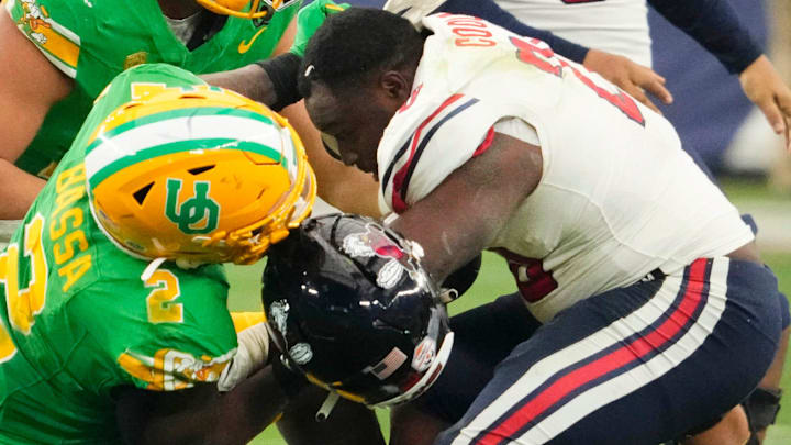 Liberty Flames running back Quinton Cooley (20) loses his helmet after being tackled by Oregon Ducks linebacker Jeffrey Bassa (2) in the first half during the Fiesta Bowl at State Farm Stadium in Glendale on Jan. 1, 2024.