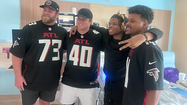 Atlanta Falcons players Matthew Cindric (73), JD Bertrand (40) and Jamal Agnew (14) take a photo with a patient at the Arthur M. Blank Hospital.