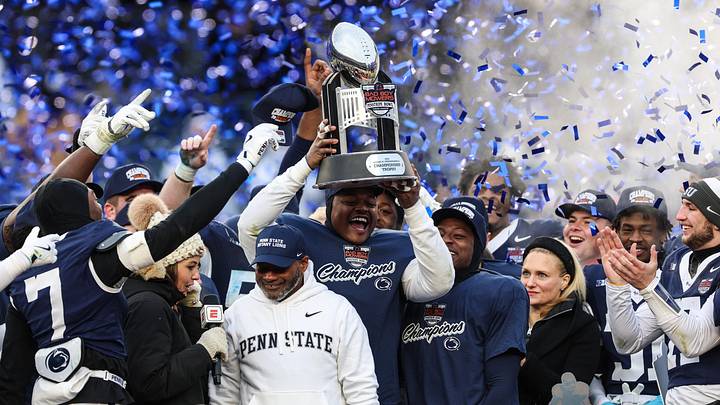 Penn State Nittany Lions players celebrate with the George M. Steinbrenner Trophy after defeating the Clemson Tigers in the 2025 Pinstripe Bowl at Yankee Stadium.