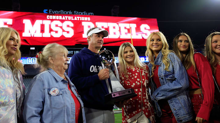 Mississippi Rebels head coach Lane Kiffin, center left, poses with the Ash Verlander Champions Trophy with his family after the game of the TaxSlayer Gator Bowl.