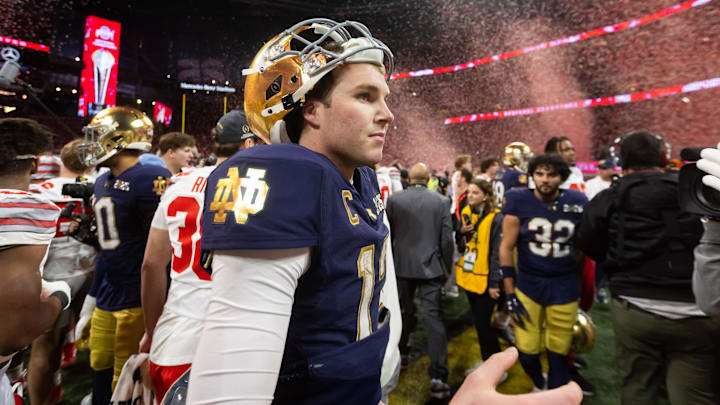 Jan 20, 2025; Atlanta, GA, USA; Confetti falls as Notre Dame Fighting Irish quarterback Riley Leonard (13) walks off the field after losing to the Ohio State Buckeyes in the CFP National Championship college football game at Mercedes-Benz Stadium.  