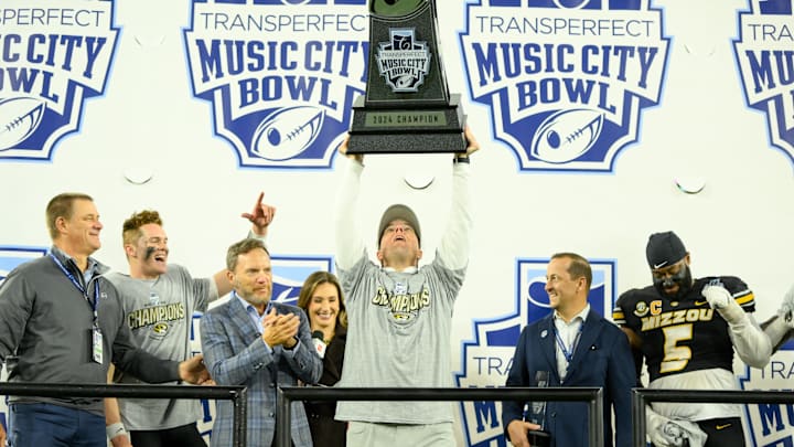 Dec 30, 2024; Nashville, TN, USA;  Missouri Tigers head coach Eliah Drinkwitz holds the trophy up above his head against the Iowa Hawkeyes during the trophy presentation  at Nissan Stadium. Mandatory Credit: Steve Roberts-Imagn Images