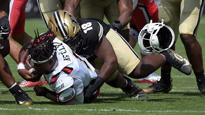 Aug 30, 2025; West Lafayette, Indiana, USA; Ball State Cardinals quarterback Kiael Kelly (1) loses his helmet while being tackled by Purdue Boilermakers defensive lineman Demeco Kennedy (18) during the first quarter at Ross-Ade Stadium. Mandatory Credit: Marc Lebryk-Imagn Images Aug 30, 2025; West Lafayette, Indiana, USA; Ball State Cardinals quarterback Kiael Kelly (1) loses his helmet while being tackled by Purdue Boilermakers defensive lineman Demeco Kennedy (18) during the first quarter at Ross-Ade Stadium. Mandatory Credit: Marc Lebryk-Imagn Images
