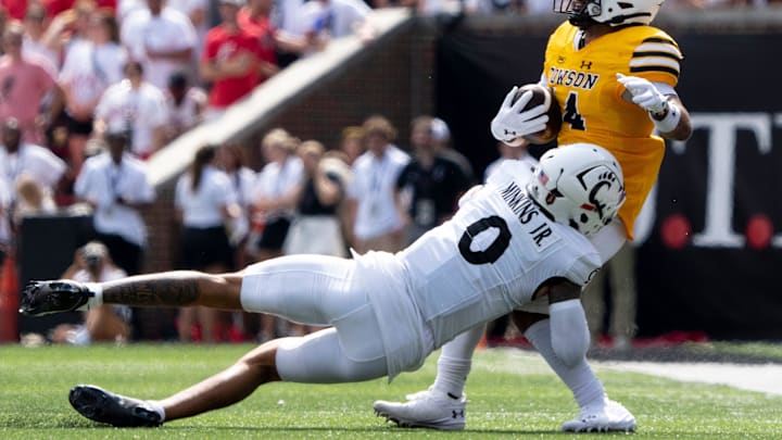 Cincinnati Bearcats defensive back Josh Minkins (0) tackles Towson Tigers wide receiver Lukkas Londono (14) in the first quarter of the College Football game at Nippert Stadium in Cincinnati on Saturday, Aug. 31, 2024.