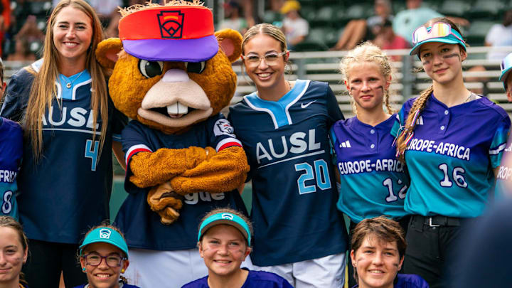 AUSL pitchers Georgina Corrick (4) and Sam Landry (20) pose for a picture with Europe-Africa's team and Little League Softball World Series mascot ahead of Tuesday, August 5 games.
