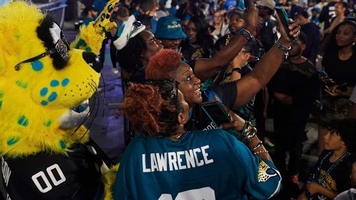 Jacksonville Jaguars mascot Jaxson de Ville is photographed by Laveenya Schuler, center, during the