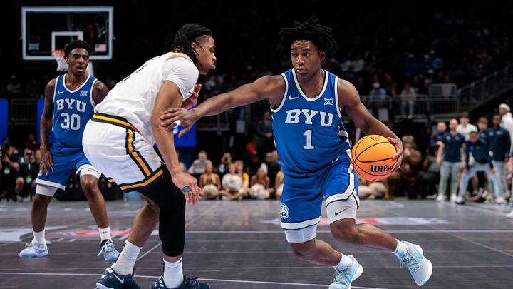 Mar 11, 2026; Kansas City, MO, USA; BYU Cougars guard Robert Wright III (1) drives to the basket around West Virginia Mountaineers guard Chance Moore (13) during the second half  at T-Mobile Center. Mandatory Credit: William Purnell-Imagn Images